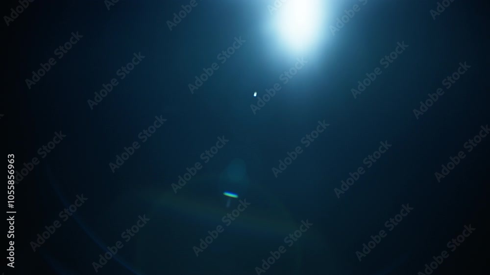 Abstract blue lens flare on black background. Slow motion. 