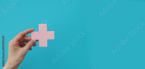 A female hand gracefully holds a white plus sign, representing medical care and support on World Health Day against a turquoise background