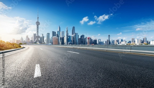 Open road leading towards a modern city skyline under a bright blue sky.