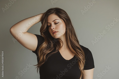 A woman in a casual black T-shirt strikes a pose under soft studio lighting, against a smooth gray backdrop.