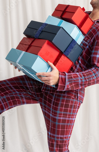Person in Plaid Pajamas Holding a Large Stack of Red and Blue Gift Boxes for the holidays 