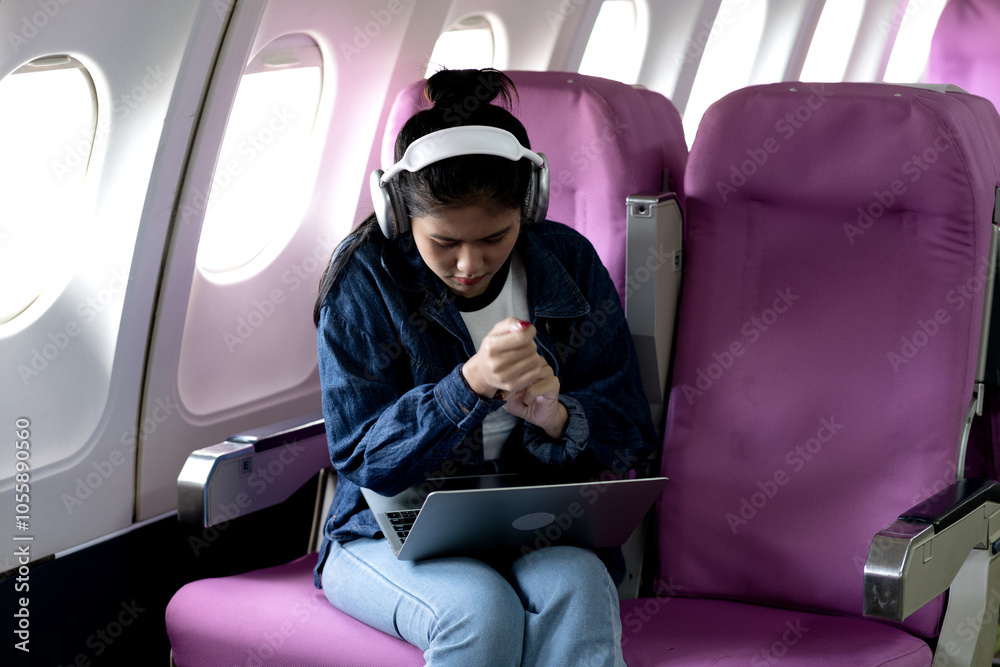 Young woman using a notebook on an airplane in a comfortable Young woman using a notebook on an airplane in a comfortable