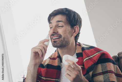 Young man enjoying leisure time indoors with tissue and nasal spray in cozy home setting