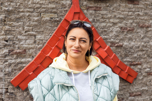 Confident woman in casual wear posing against decorative brick wall photo