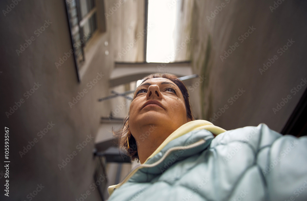 Fototapeta premium Low angle view of person in narrow urban alley with dramatic perspective