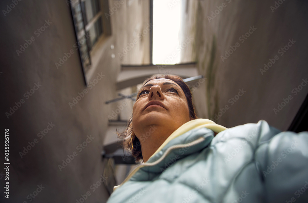 Woman in urban alley looking upwards in winter coat Woman in urban alley looking upwards in winter coat
