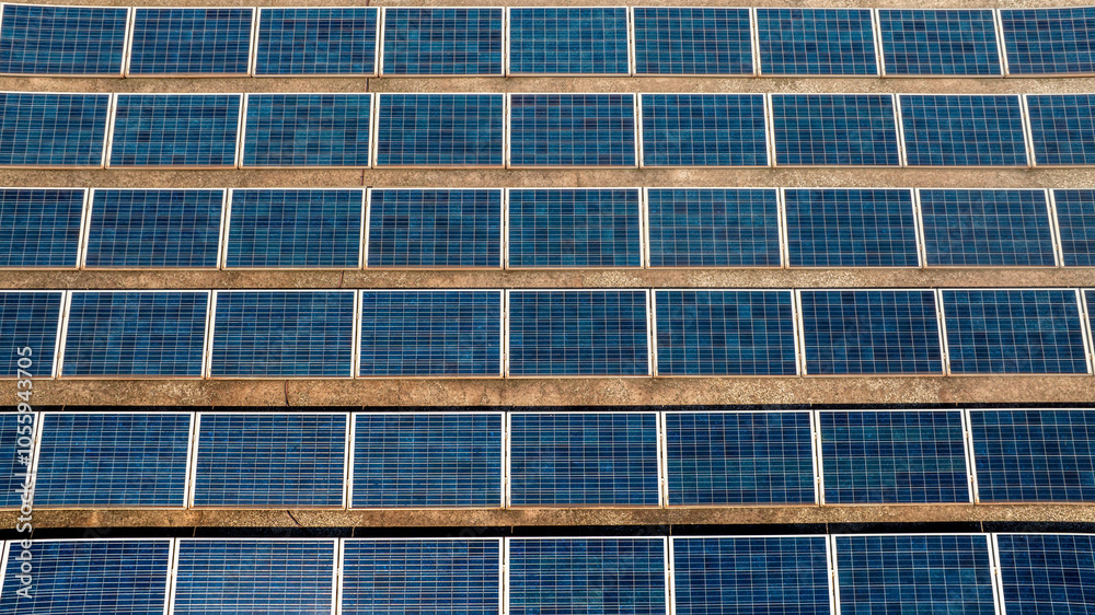 Aerial view of many solar panels on a sunny day. They are located on the roof of a building. Aerial view of many solar panels on a sunny day. They are located on the roof of a building.