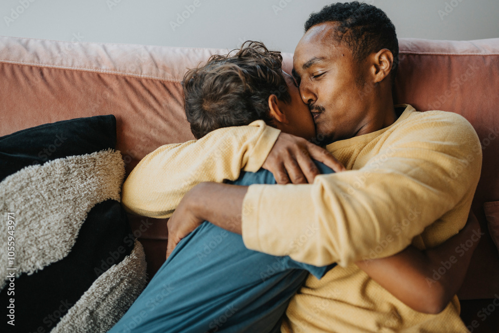 Father kissing son while sitting on sofa at home Father kissing son while sitting on sofa at home