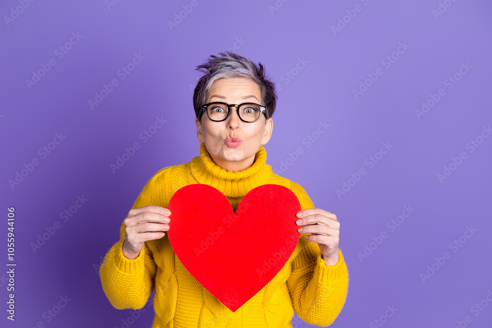 Photo of cheerful pretty lady dressed knitted jumper sending you kiss holding heart empty space isolated purple color background Photo of cheerful pretty lady dressed knitted jumper sending you kiss holding heart empty space isolated purple color background