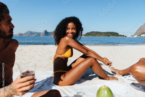 Young woman relaxing on a picnic blanket and enjoying a day with friends at the beach photo