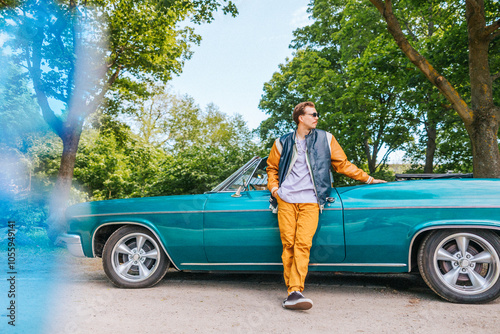 Fashionable man with hand in pocket standing near vintage car at park photo