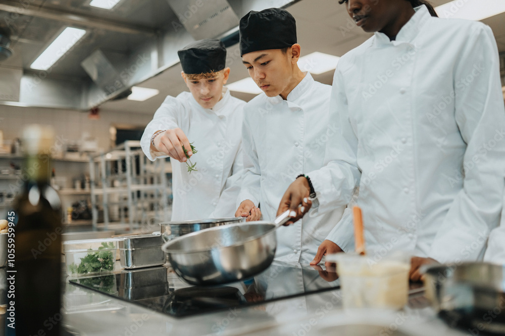 © Maskot - Male teenage trainees preparing food by female colleague holding saucepan in commercial kitchen © Maskot - Male teenage trainees preparing food by female colleague holding saucepan in commercial kitchen