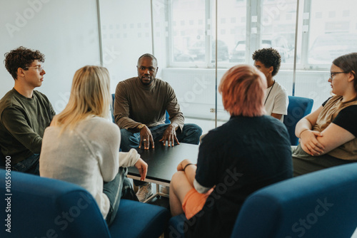 Mental health professional discussing with male and female students during group therapy photo