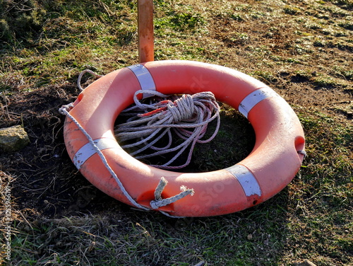 circular lifebuoy on the ground, fallen after storm in the coast. Safety and rescue concept. Ring buoy to save life  photo