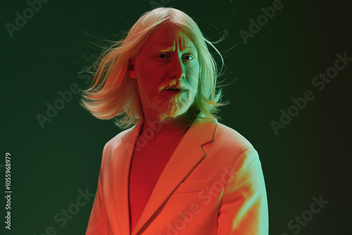 Portrait of a man with long white hair and a striking expression against a gradient background The subject wears a light colored suit, creating a bold visual contrast photo