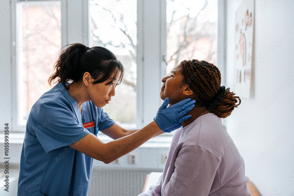 Focused female medical expert checking lymph nodes of young patient in examination room at hospital Focused female medical expert checking lymph nodes of young patient in examination room at hospital