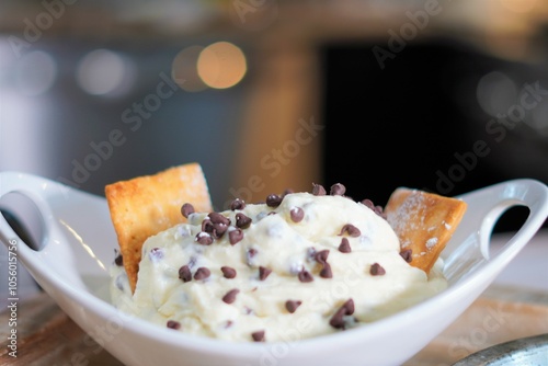 A delicious bowl of creamy and sweet cannoli dip with milk chocolate mini chips.  Dessert dip with cannoli chips, mini chocolate chips and creamy cannoli filling.