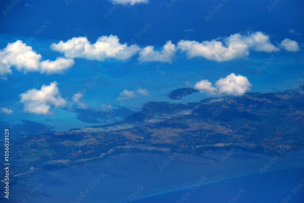 Naklejka premium Aerial view from window airplane sky summer tropical blue sky fluffy white cloud summertime on light sunny day cloudscape ocean seascape. Clear bright blue skyline spring sunlight climate background