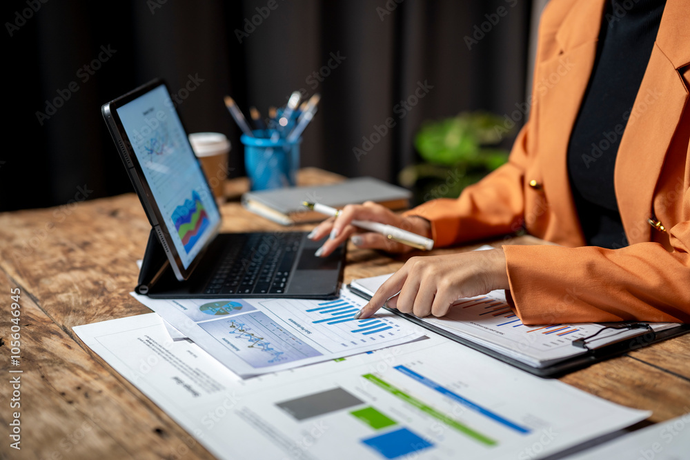 Businesswoman analyzing financial charts on desk with laptop Businesswoman analyzing financial charts on desk with laptop