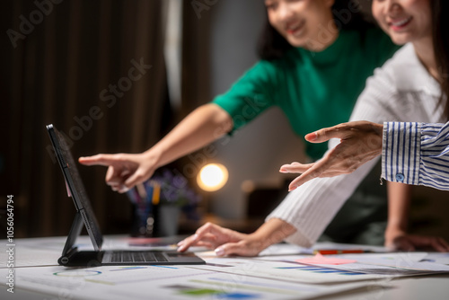 Two women are looking at a computer screen and pointing at something