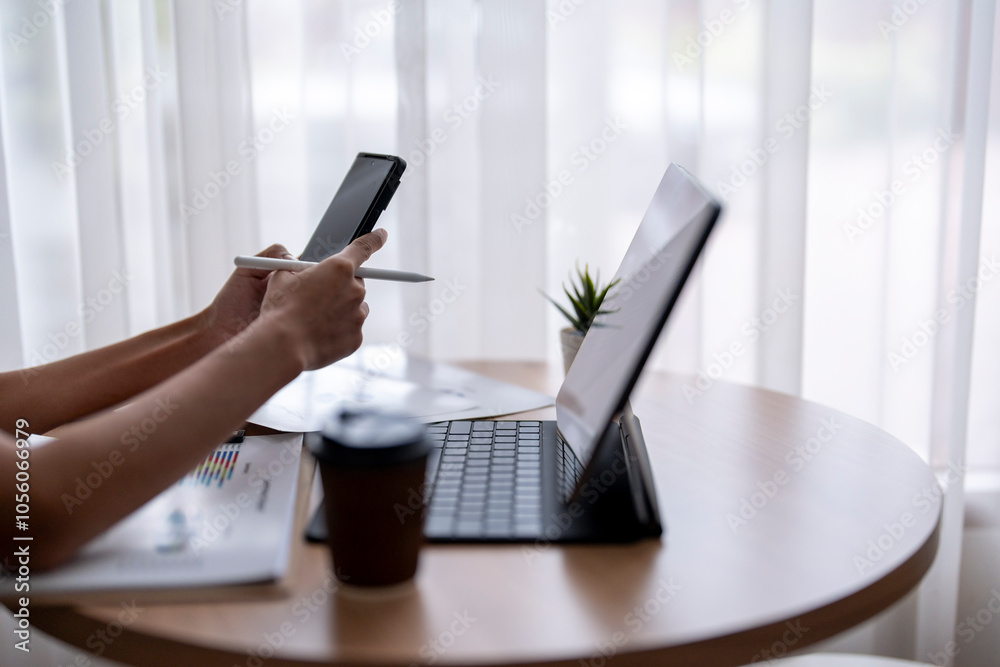 Fototapeta premium Businesswoman using smartphone and analyzing charts on tablet at home office
