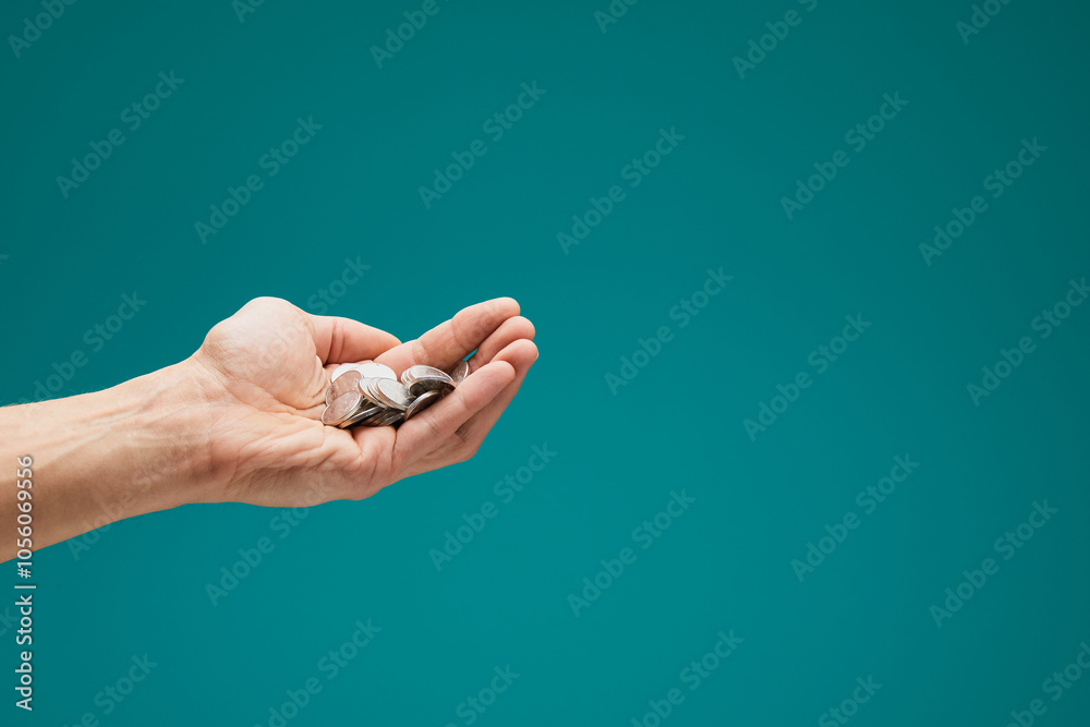 Arm holding a lot of coins, cashback, big profit. Male hand holds cash for financial income isolated on green background. Arm holding a lot of coins, cashback, big profit. Male hand holds cash for financial income isolated on green background.