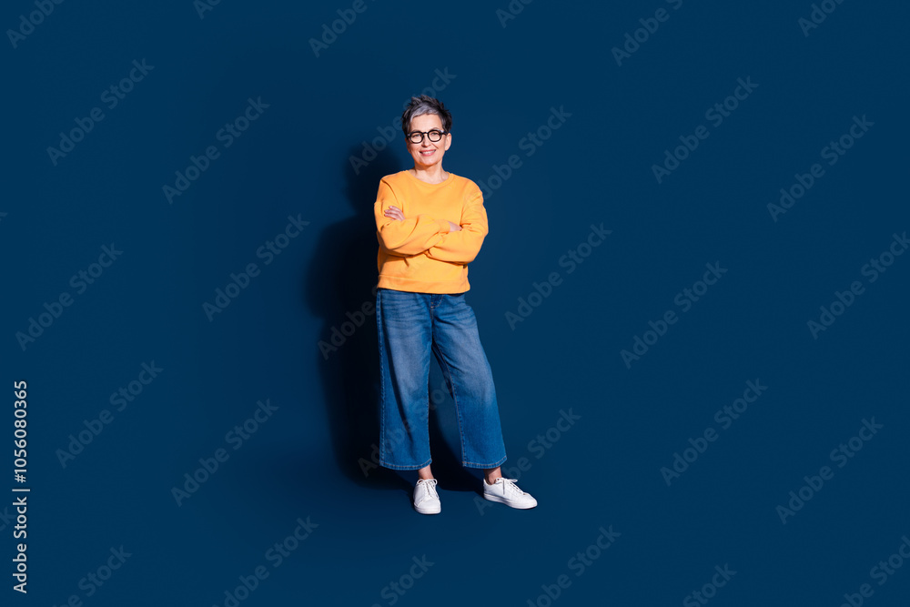 Full size photo of attractive mature woman crossed hands confident dressed stylish yellow clothes isolated on dark blue color background Full size photo of attractive mature woman crossed hands confident dressed stylish yellow clothes isolated on dark blue color background