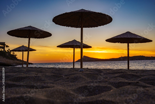 Colorful sunset on the island of Kalymnos (Greece). View over the beach with umbrellas to the sea to the island of Telendos photo