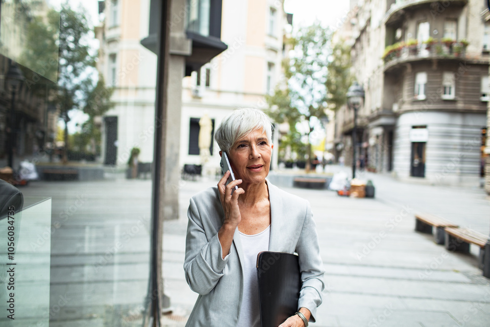 Smiling senior businesswoman using smartphone downtown Smiling senior businesswoman using smartphone downtown