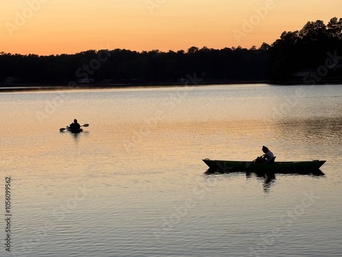Sunset lake view through pine trees summer evening two kayaks canoes paddling