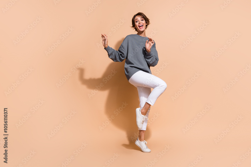 Full size photo of pretty young girl dancing charming cheerful dancer dressed stylish gray outfit isolated on beige color background Full size photo of pretty young girl dancing charming cheerful dancer dressed stylish gray outfit isolated on beige color background