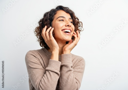 Smiling woman in brown sweater looking away with hands on face