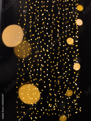 A captivating background featuring cascading golden bokeh lights against a deep black backdrop. The glowing orbs evoke a warm, festive, and elegant atmosphere, perfect for use in holiday, celebration,