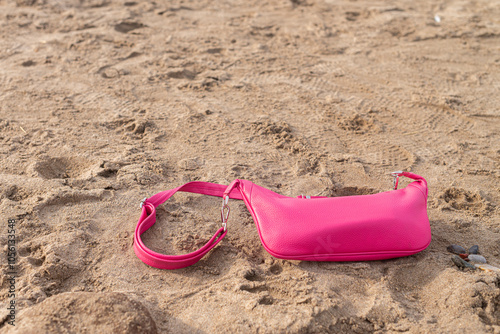Cartera rosa de mujer sobre la arena