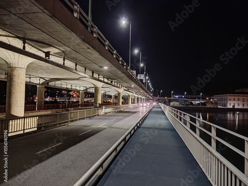 A nighttime view of an illuminated bridge with symmetrical streetlights and pathways