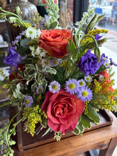 Bouquet of flower blooms at florist. Red orange roses, purple, daisies, green yellow
