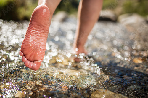 Close-up of foot wading through clear water in a stream photo