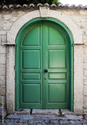 Green old wooden door with stone wall.