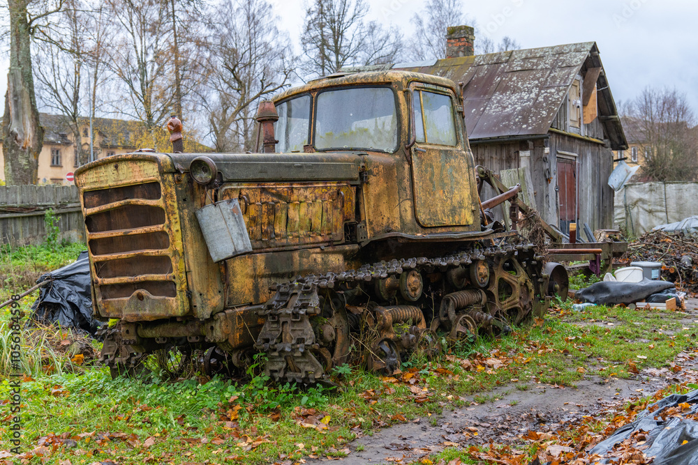 Old agricultural crawler tractor DT-75. Manufactured during Soviet times. The backyard of an old half-collapsed house. Old agricultural crawler tractor DT-75. Manufactured during Soviet times. The backyard of an old half-collapsed house.