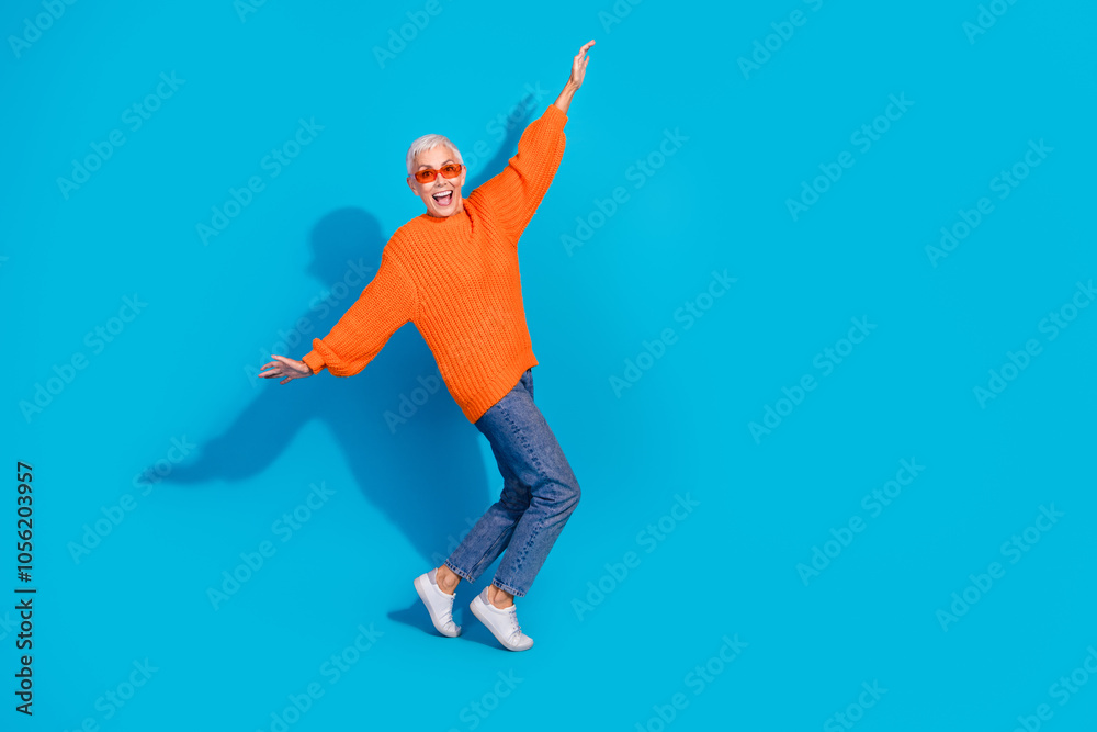 Fototapeta premium Photo of carefree crazy old woman have fun raise hands fly wings plane isolated blue color background