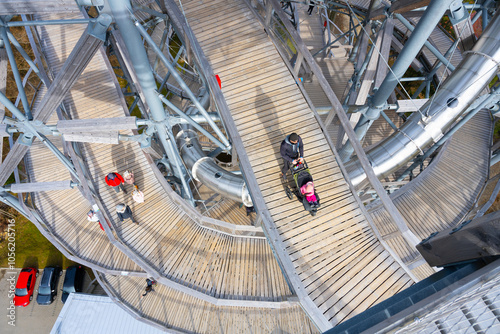 Tourists walk along the wooden pathways of the Sky Walk Tower in Swieradow Zdroj, enjoying panoramic views of the Jizera Mountains and the surrounding landscape on a beautiful day. photo