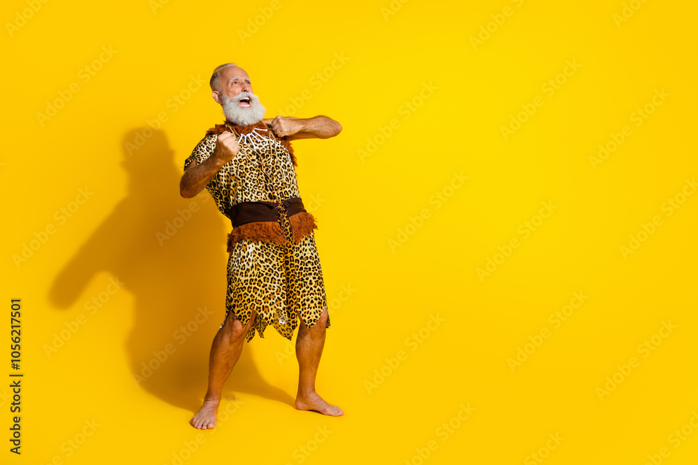 Full length photo of handsome cool neanderthal guy wear leoprad skin beating fists chest emtpy space isolated yellow color background Full length photo of handsome cool neanderthal guy wear leoprad skin beating fists chest emtpy space isolated yellow color background