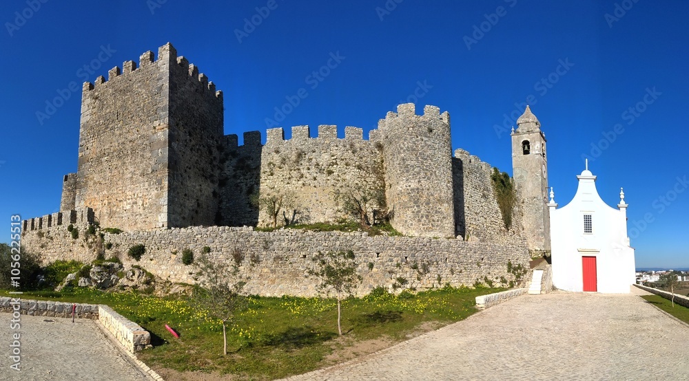 This image showcases a historic stone castle with formidable, crenelated walls and towers, bathed in sunlight against a clear, vibrant blue sky. This image showcases a historic stone castle with formidable, crenelated walls and towers, bathed in sunlight against a clear, vibrant blue sky.