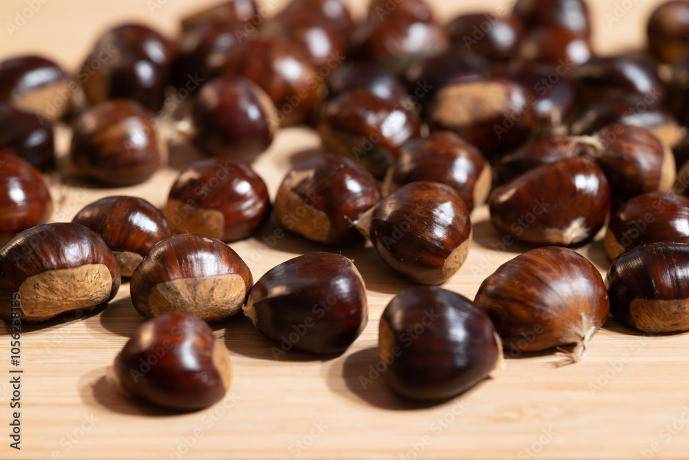 Close-up of tasty sweet chestnuts, from the castanea sativa tree, with shiny red-brown shells aka copule on a wooden table Close-up of tasty sweet chestnuts, from the castanea sativa tree, with shiny red-brown shells aka copule on a wooden table