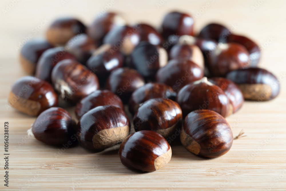Fresh raw chestnuts with shiny brown shells on a wooden table Fresh raw chestnuts with shiny brown shells on a wooden table