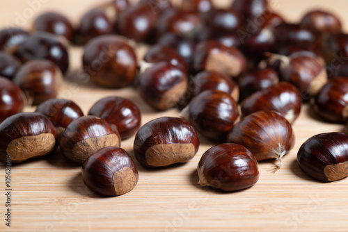 Pile of fresh raw chestnuts with shiny brown shells on a wooden table