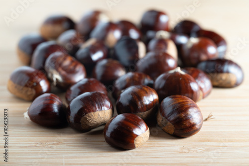 Fresh raw chestnuts with shiny brown shells on a wooden table