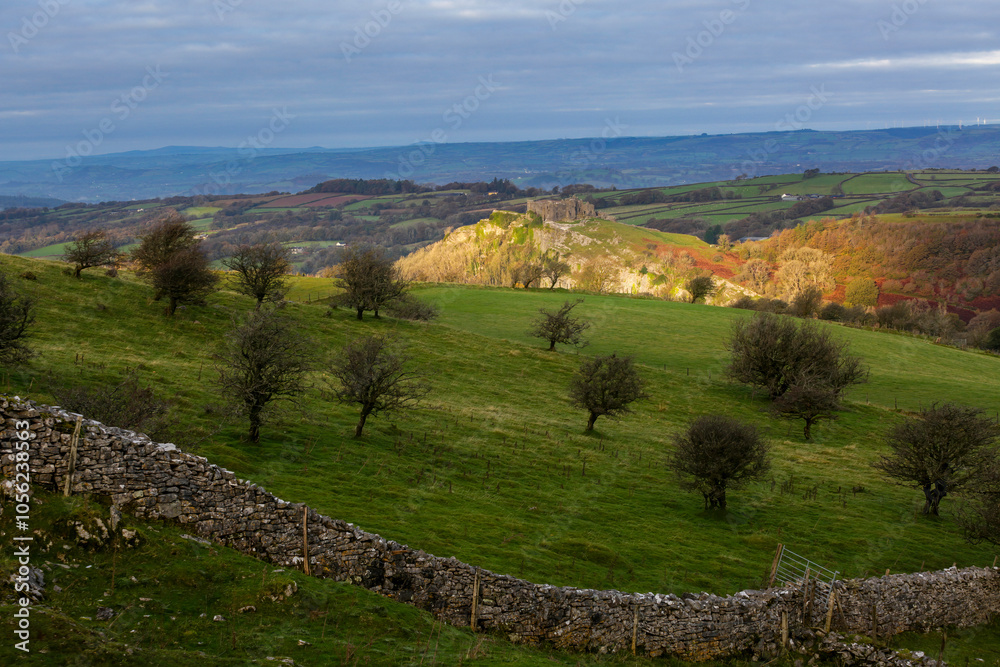 Naklejka premium Carreg Cennen castle sitting high on a hill basking in morning sunlight in Carmarthenshire, South Wales UK 