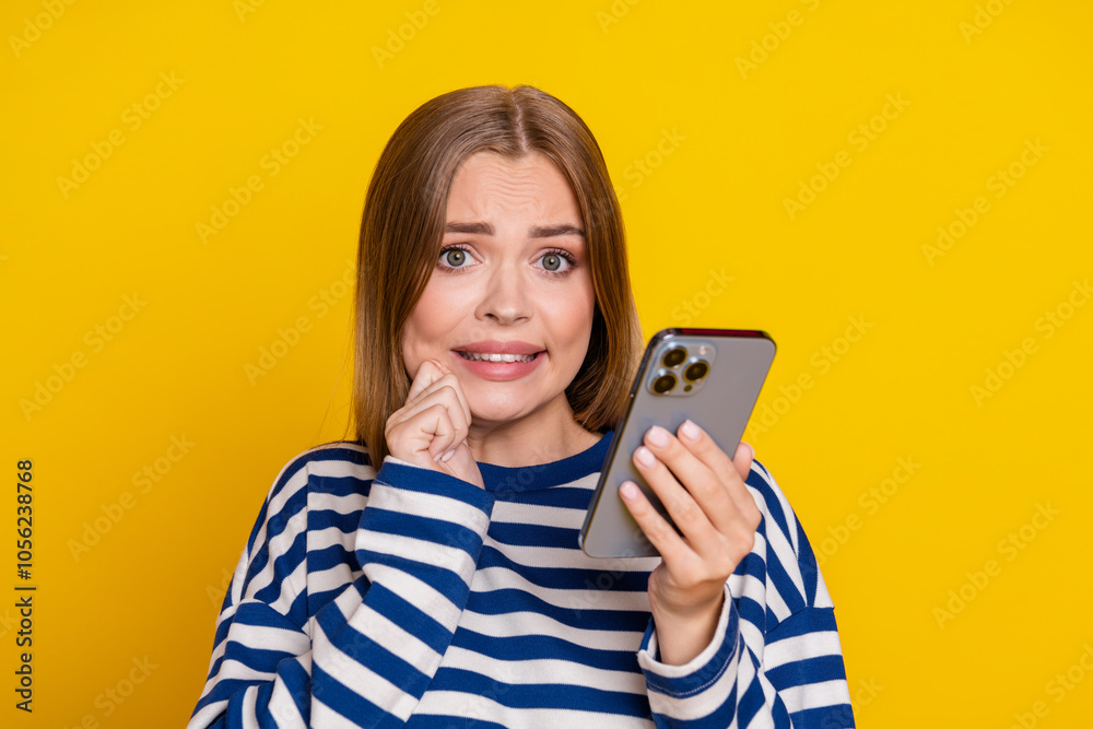 Photo of anxious embarrassed cute woman wear striped stylish sweatshirt isolated on yellow color background Photo of anxious embarrassed cute woman wear striped stylish sweatshirt isolated on yellow color background