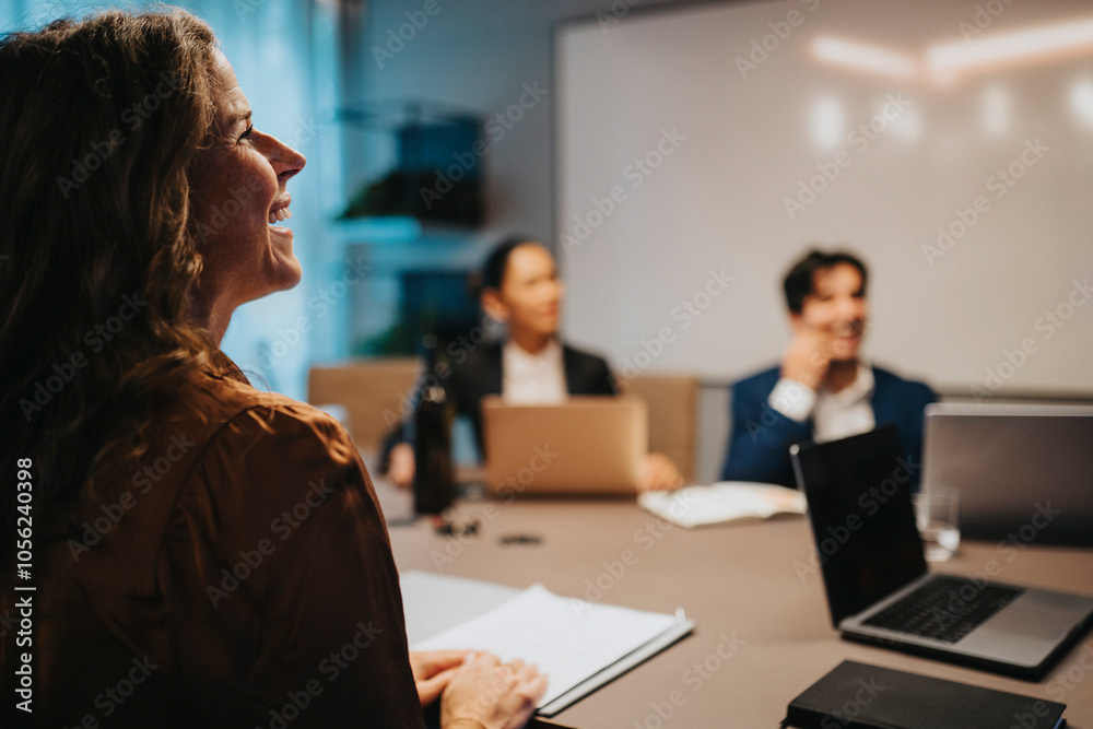 Happy businesswoman sitting at desk in board room